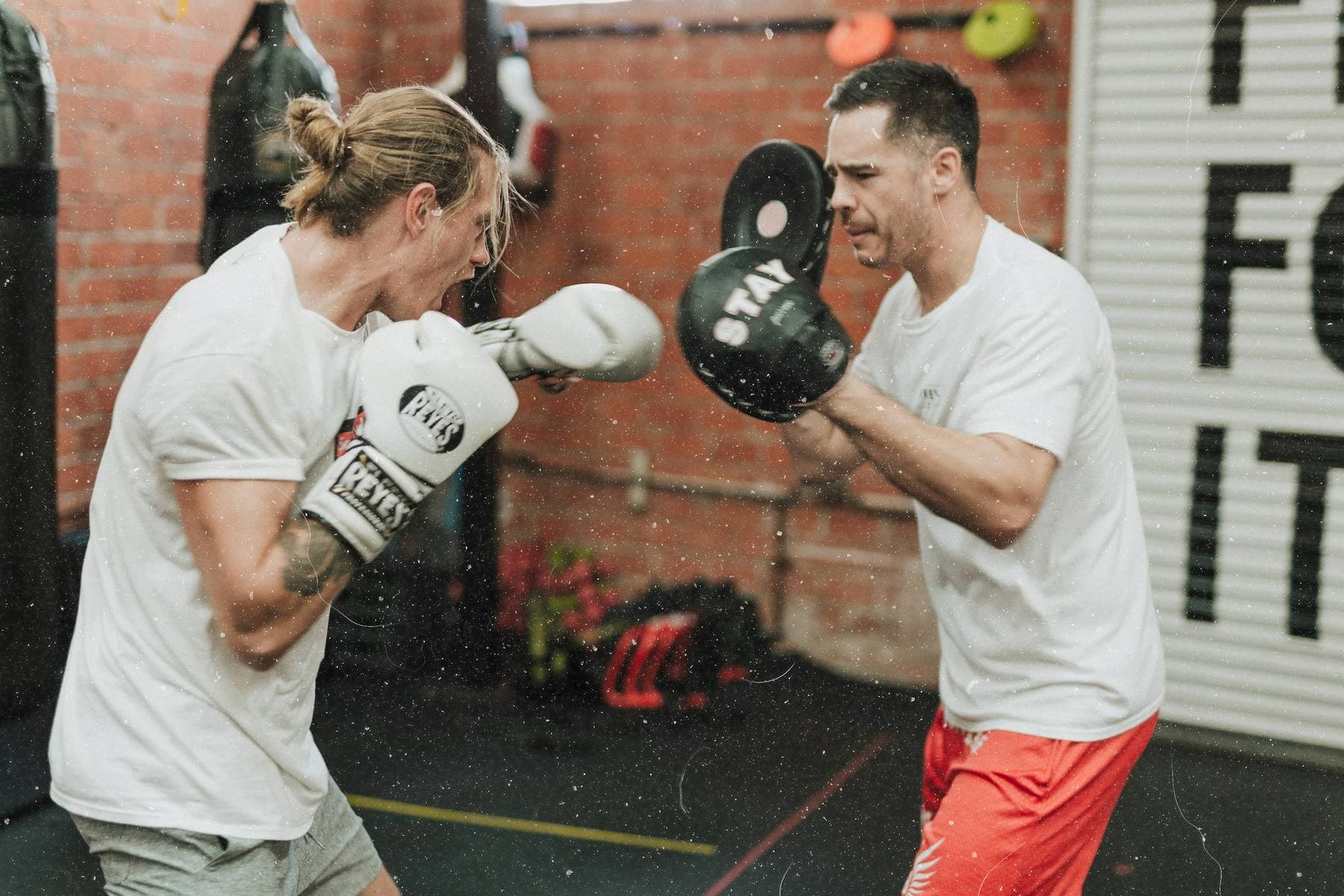 Trainer hält die Pratzen, ein Schüler schlägt mit Boxhandschuhen