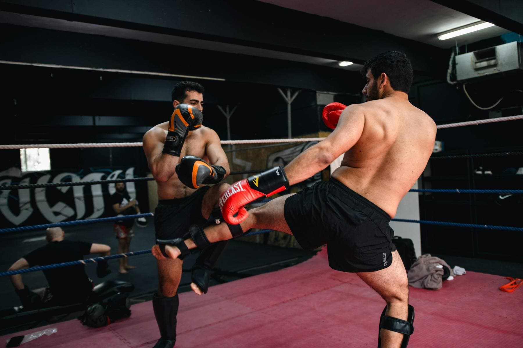 Zwei Kickboxer beim Sparring im Ring: einer tritt, der andere blockt mit dem Schienbein