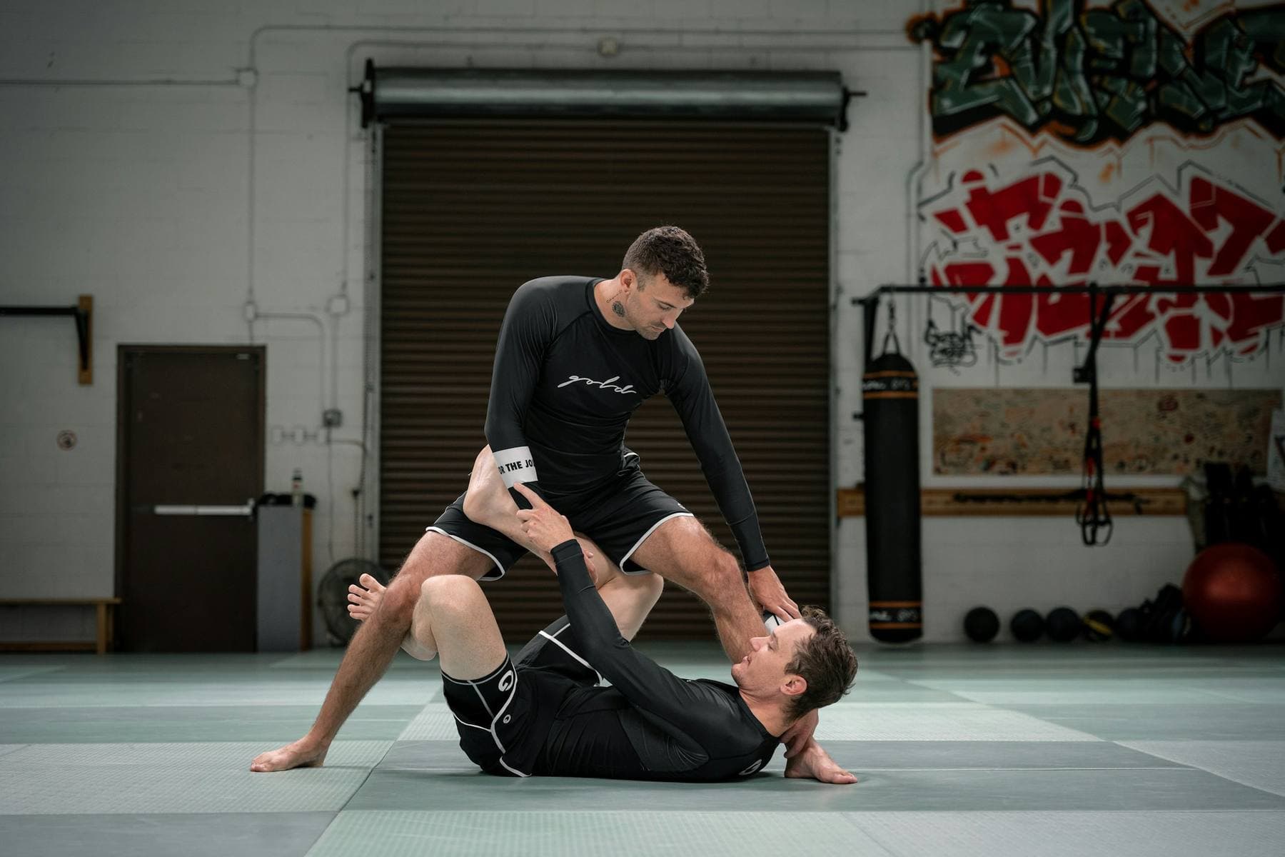Zwei Sportler in Rashguards beim NoGi-Training auf der Matte